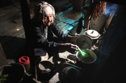 A grandmother cooking with makeshift tools 