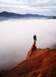 man stands on a red cliff 